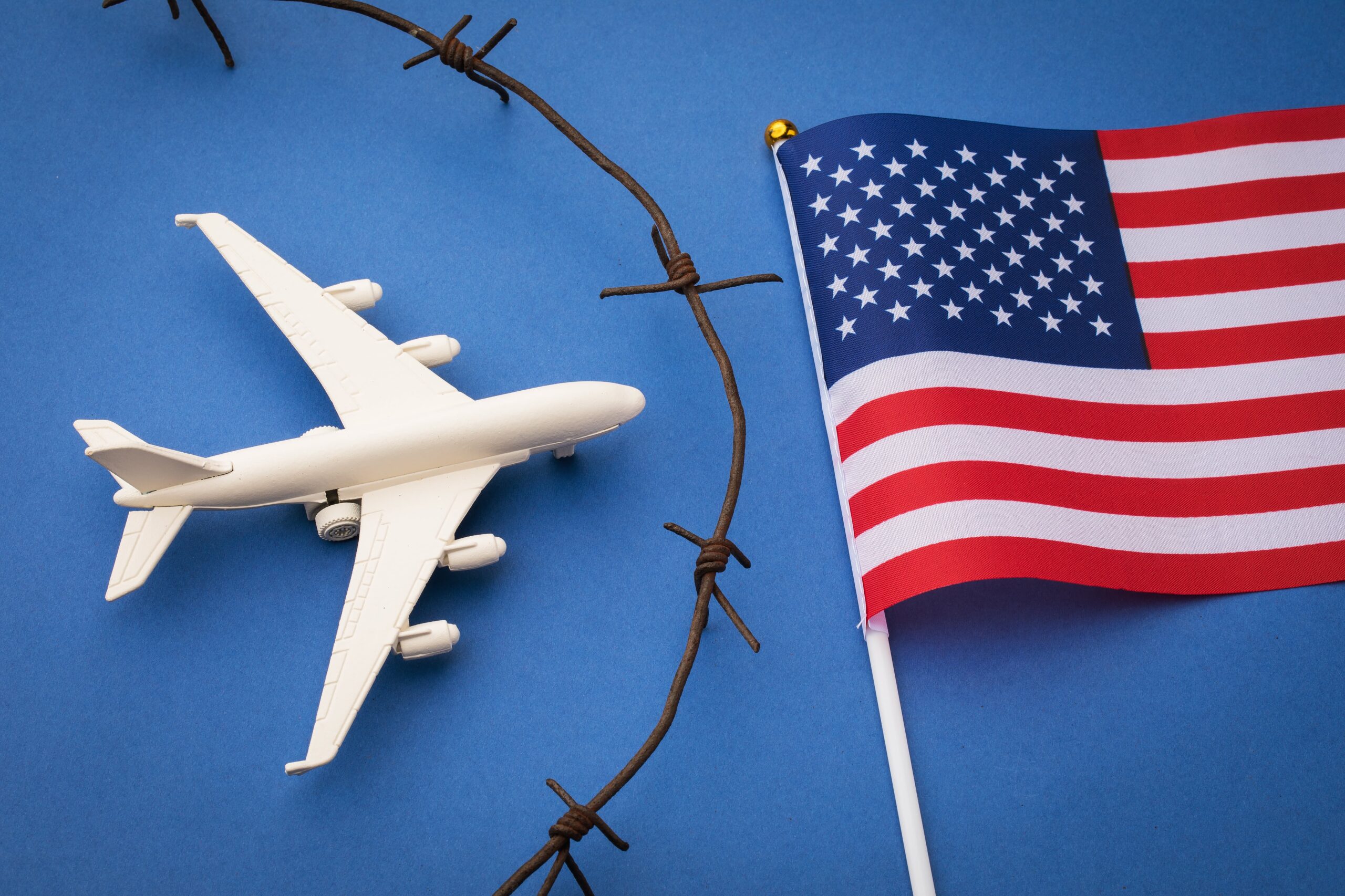 usa-closed-airspace-concept-toy-plane-barbed-wire-flag-blue-background